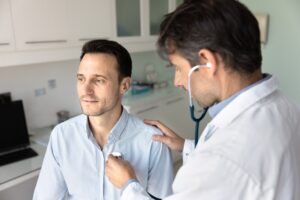 doctor examining man with stethoscope on chest
