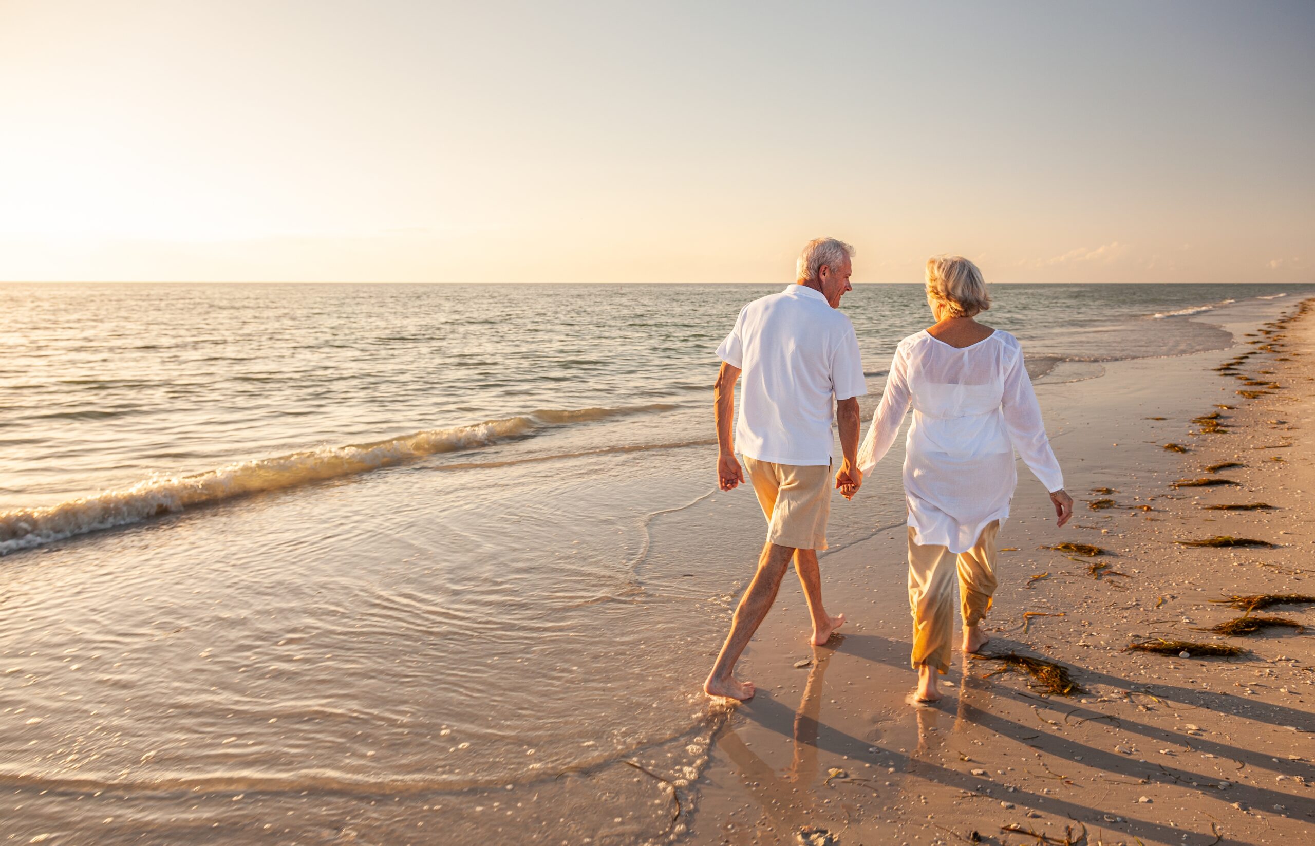 happy old senior man and woman walking on beach