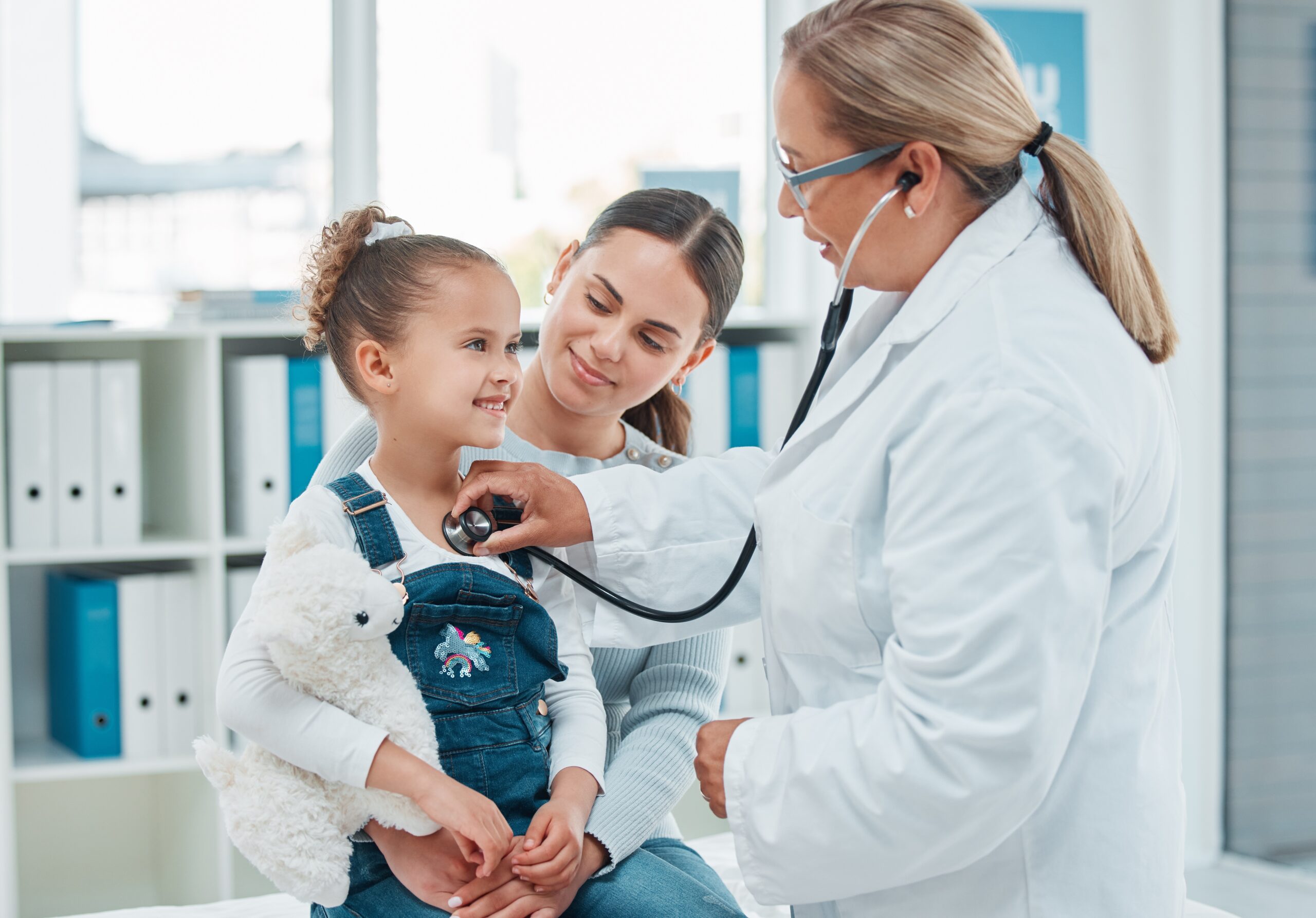 child and mother at exam with doctor using stethescope