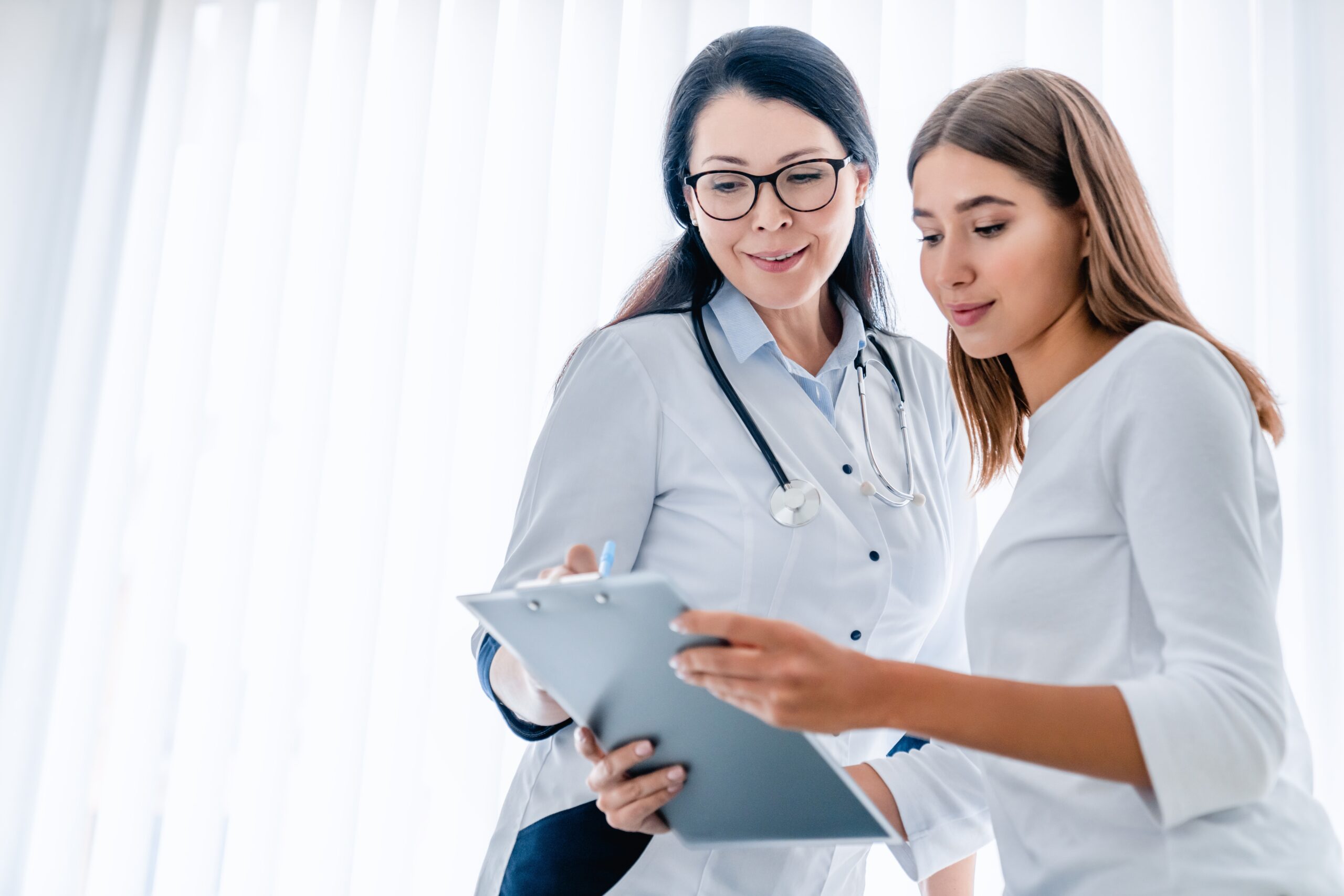 woman doctor and her female patient looking at clipboard