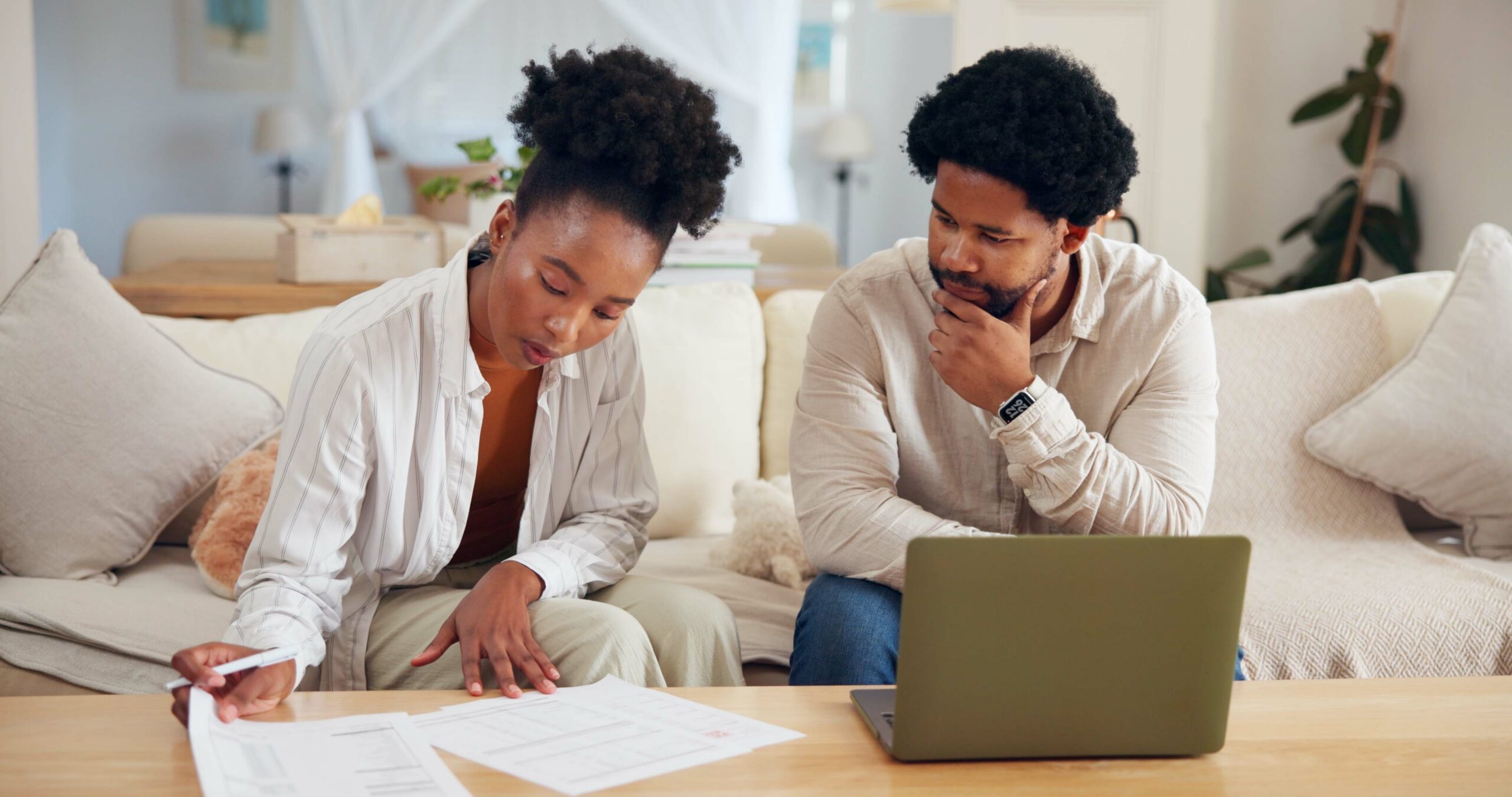 couple on sofa reviewing documents and laptop